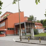 Glavni ulaz i fasada zgrade KBC Zvezdara (Gradska bolnica) u Beogradu sa prilazom i portirnicom.